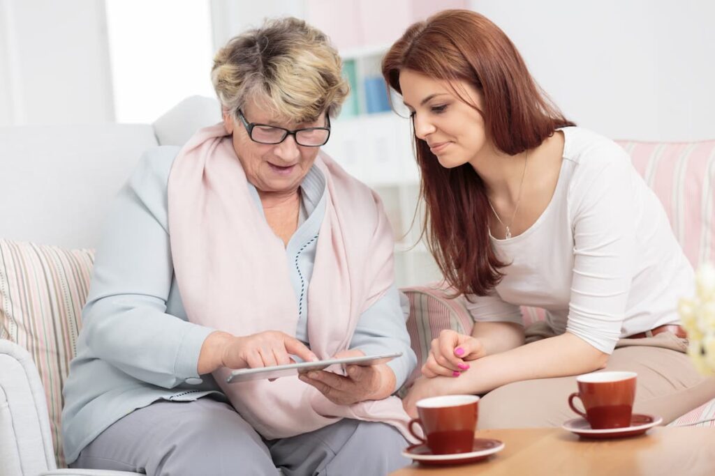 Stonecreek of Littleton | Senior woman looking at photos with caregiver - Willowbrook memory care