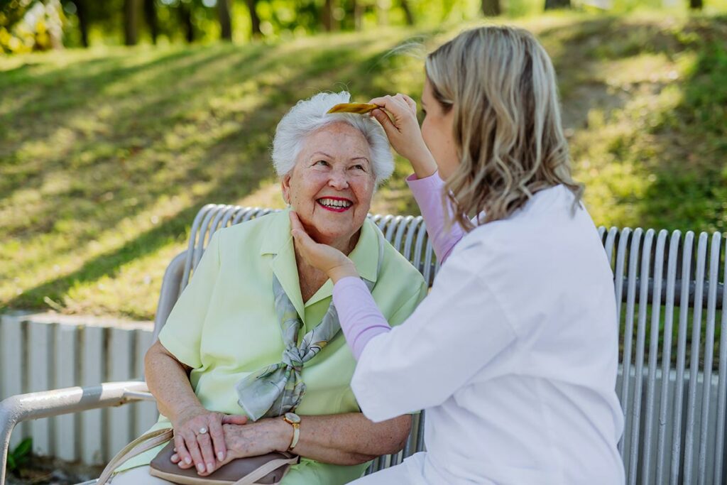 The Avenues of Fort Bend | Senior woman smiling while getting her hair combed by her caregiver