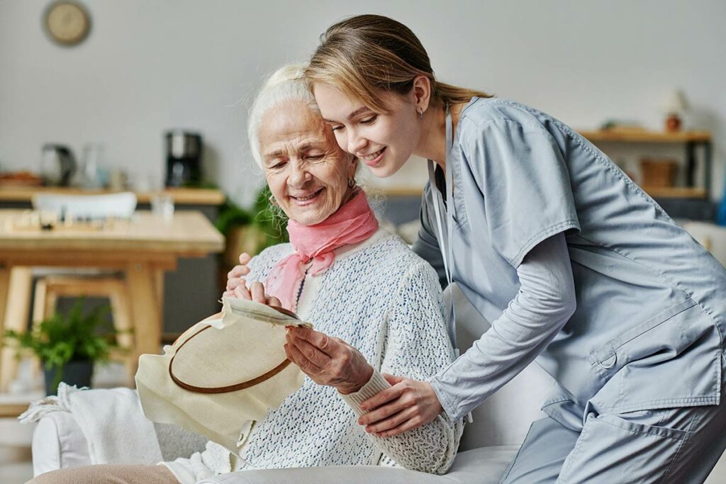 Tech Ridge Oaks | Senior woman showing caregiver her needlepoint project