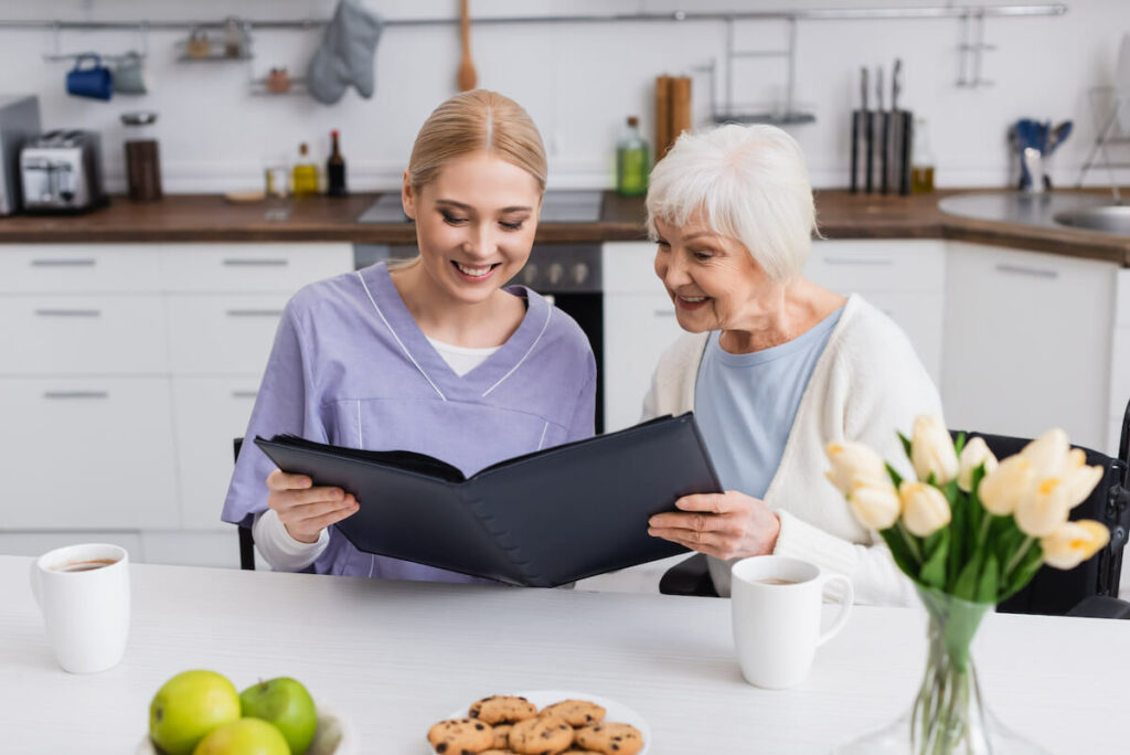 StoneCreek of Copperfield | Senior with caregiver looking at recipe book in kitchen